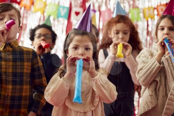 Group Of Children Celebrating At Birthday Party With Paper Hats And Party Blowers