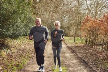 Senior Couple Exercising In Autumn Countryside During Covid 19 Lockdown