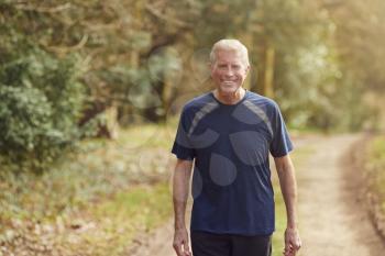Portrait Of Smiling Senior Man Running In Autumn Countryside Exercising During Covid 19 Lockdown