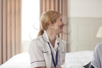 Smiling Female Doctor Making Home Visit To Patient In Bedroom