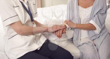 Close Up Of Female Doctor Making Home Visit To Senior Woman For Medical Check Offering Reassurance