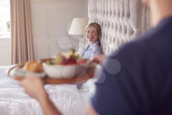 Man Bringing Woman Breakfast In Bed To Celebrate Wedding Anniversary