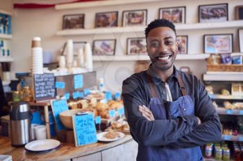 Portrait Of Smiling Male Owner Of Coffee Shop Standing By Counter