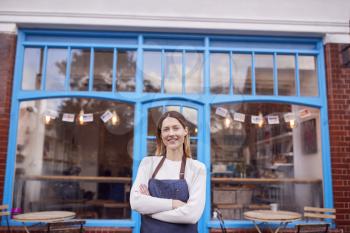 Portrait Of Smiling Female Small Business Owner Standing Outside Shop On Local High Street