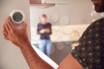Close Up Of Man Adjusting Wall Mounted Digital Central Heating Thermostat Control At Home