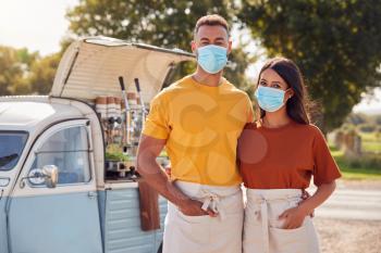 Portrait Of Couple Wearing Face Masks Running Independent Mobile Coffee Shop Standing Next To Van
