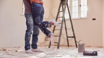 Close Up Of Couple Hugging As They Decorate Room In New Home Together