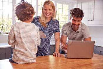 Family With Pregnant Mother At Home Buying Products Or Services Online Using Laptop