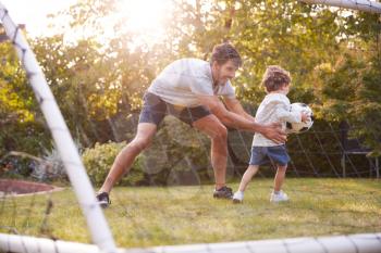 Father With Son Having Fun In Park Or Garden Playing Soccer Together