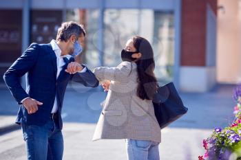 Businessman And Businesswoman Having Socially Distanced Meeting Outdoors Touching Elbows