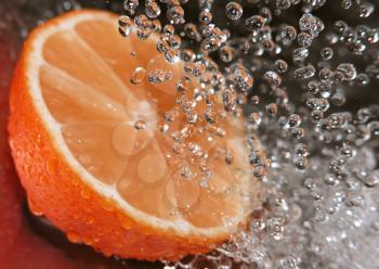 Water drops falling onto an orange - focus is on the water drops