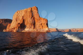 Travel voyage by boat on Lake Powell. Picturesque waves astern the ship. Sunset rays illuminate the rocks on the shore of the lake. Arizona, USA.