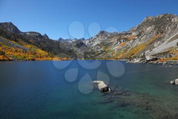Mountain fishing lake with transparent azure water.Sunny autumn midday