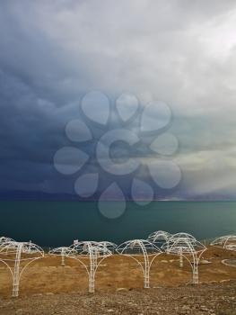 A beach canopies on deserted coast of the Dead Sea in a thunder-storm