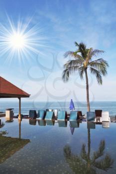 The luxurious marble pool on the island of Koh Samui. Palm tree and beach chairs are reflected in the smooth surface of the water