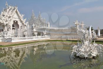 Fantastic beauty White Temple. Perfectly well decorated facade is reflected in a pond with live small fishes
