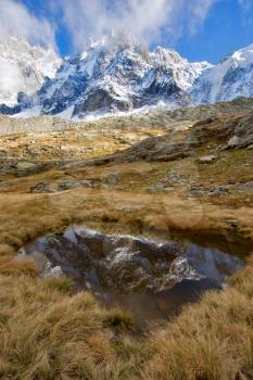  A small pool reflecting huge mountain in a snow  