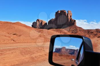 The famous cliff Camel and other cliff of red sandstone in Monument Valley are reflected in the car mirror. Navajo Reservation in the U.S.