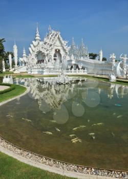 White fairy palace. Beautifully reflected in a pond with live fish. Built in the style of the new Thai architecture