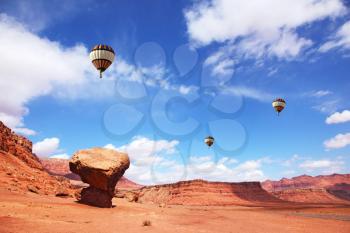 Huge balloons with the passenger basket flying over the picturesque cliffs of red sandstone
