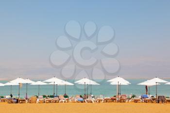 Sun beds, chairs, umbrellas and awnings on the beach luxury hotel on the Dead Sea in Israel. Sunny spring day