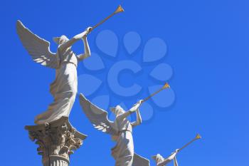 The statues of winged troubadours against the blue sky decorated capitals of the columns.