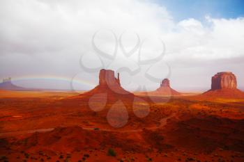 Famous mittens of red sandstone in a fog after the storm and a rainbow in the sky