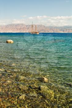 Stones and a sailing yacht in coastal waters of a resort Eilat in Israel