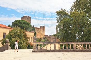The imposing medieval castle - the monastery of the Templars. A woman dressed in white photographs in the park