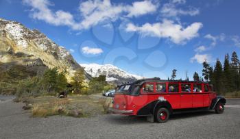 The bright red car of ancient design with tourists in cold mountains of the north