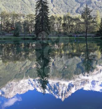 Chamonix - a famous ski resort in the French Alps. Magnificent snow-capped mountains reflected in the smooth water of the lake in the park