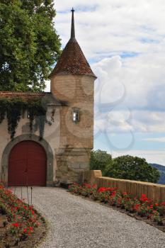 The medieval castle in Upper Savoy. Corner round tower, part of the protective walls and massive red wooden gate