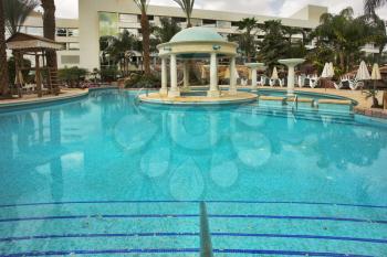 Round pavilion constructed in decorative pool with transparent water in a court yard of dear hotel