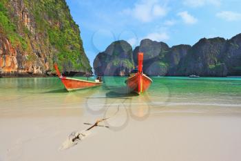  In sand approached by two tourist boats, decorated with colorful silk scarves and wreaths. Scenic green islands of Thailand coast. Emerald sea and fine white sand