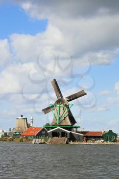 Cool windy day. Traditional windmills and economic constructions with triangular roofs on the bank of the channel