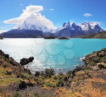 Magic beauty of the lake of Pehoe. The strong wind drives turquoise waves on the lake, grandiose rocks Los Kuernos are covered with snow and ice