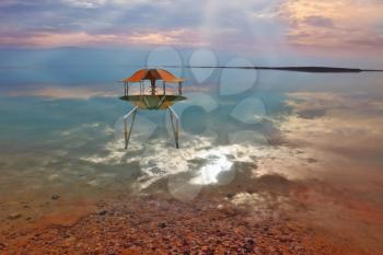  The picturesque arbor for bathers is reflected in a smooth sea surface. Fantastically beautiful optical effects at the Dead Sea.