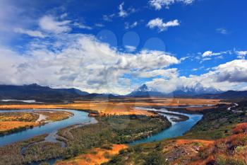 Meandering river bed of yellow autumn coast. Valley surrounded by snow-capped mountains. Glen Serrano