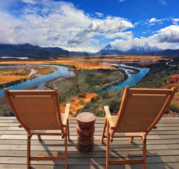  Two wooden chairs - on a wooden platform. Charming rural idyll. Clouds reflected in the smooth water of the river. A comfortable place to enjoy the beauty of the landscape.