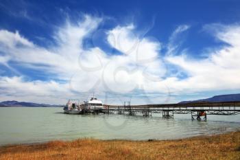 Journey into a far country.  The lake in Argentina and tourist boat at the pier