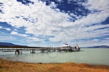 Journey into a far country.  The lake in Argentina and tourist boat at the pier