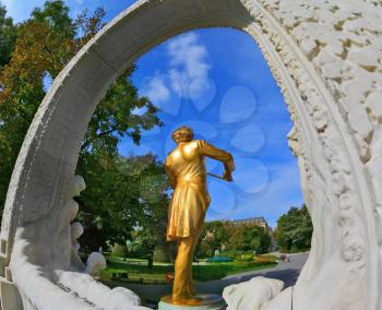 Elegant gilded statue of Johann Strauss, playing the violin in white marble arch. Park in Vienna