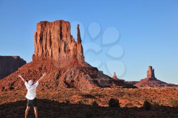 Enthusiastic tourist in Monument Valley. The famous monolith of red sandstone - Mittens.