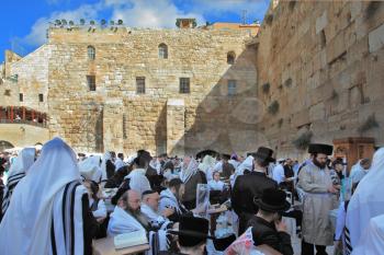 JERUSALEM, ISRAEL - SEPTEMBER 20, 2013: Morning Sukkot.  The Western Wall of the Temple in Jerusalem. Many religious Jews in traditional robes tallit gathered for prayer.