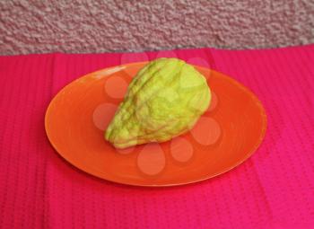 Jewish ritual fruit - yellow etrog. Background - orange plate and raspberry  napkin