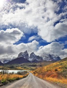 Windy day in the Chilean Patagonia. Picturesque clouds piled up in the blue sky. The gravel road goes to the famous cliffs of Los Kuernos.