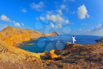  The woman ashore in a white suit for yoga carries out a pose Tree