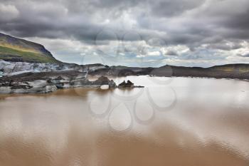  Skaftafell National Park.  Ice covered with volcanic ash. Mirror Lake, formed as a result of thawing of a glacier Vatnajokull glacier spurs. Iceland in July