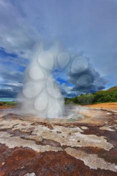 Gushing geyser Strokkur. High column of hot water and steam from the crater of the geyser. Iceland in the summer