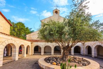 Small cozy church yard on the Sea of Galilee, Israel. Round bed with olive tree